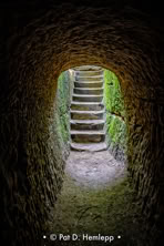 Daylight illuminates steps at the end of a tunnel carved through rock, Hocking Hills State Park, Logan, Ohio.
