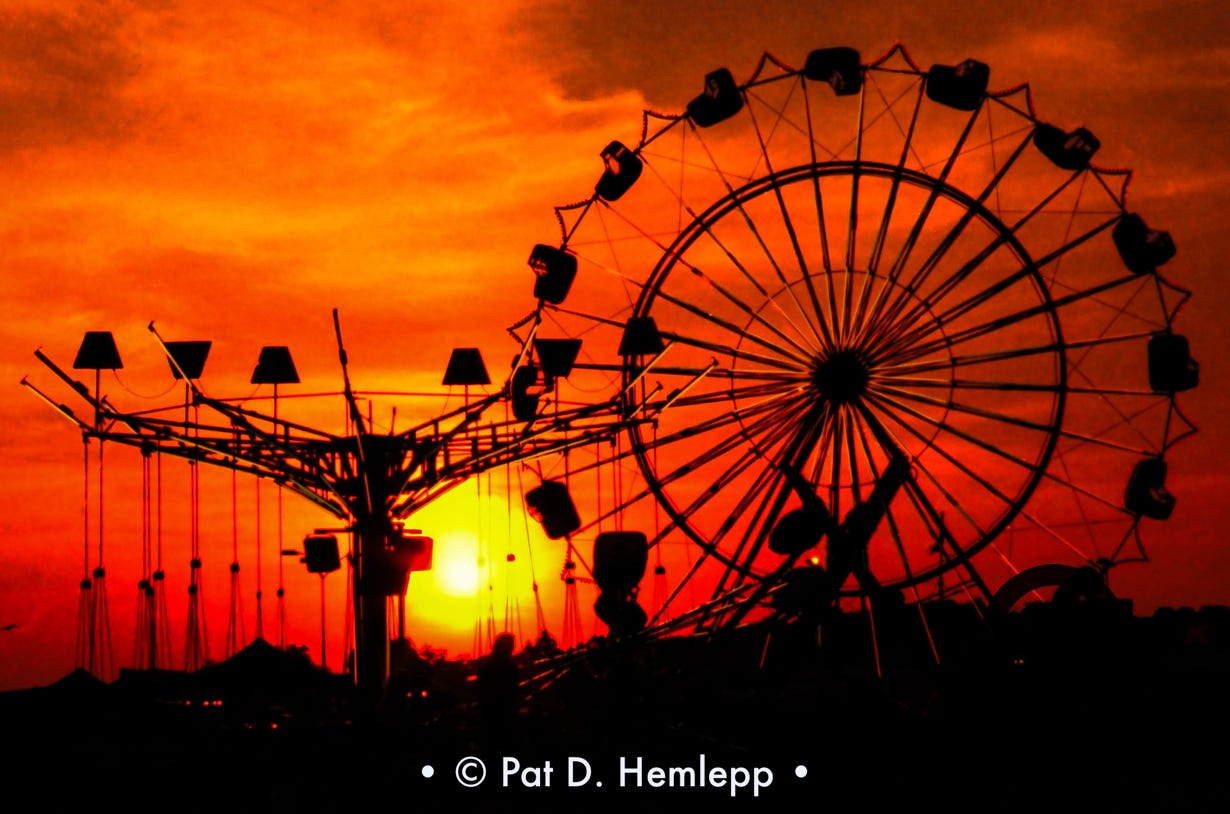 The sun sets behind carnival rides in a Kmart parking lot in Russell, Ky., June 1977.