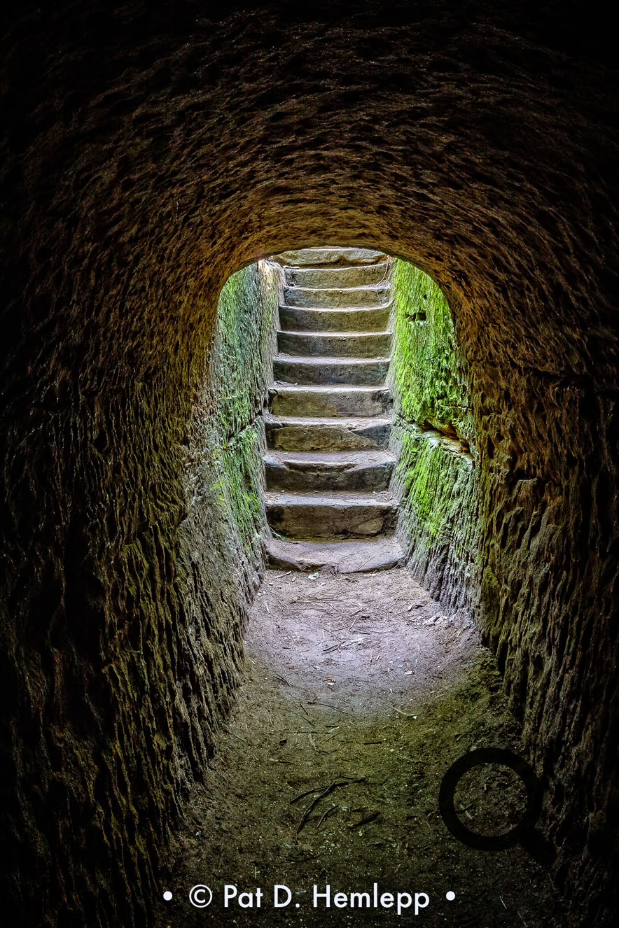 Daylight illuminates steps at the end of a tunnel carved through rock, Hocking Hills State Park, Logan, Ohio.